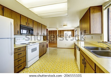 Empty kitchen room with linoleum floor, old storage cabinets and white appliances