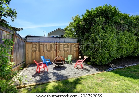 House backyard with lawn and rest area with fire pit and chairs