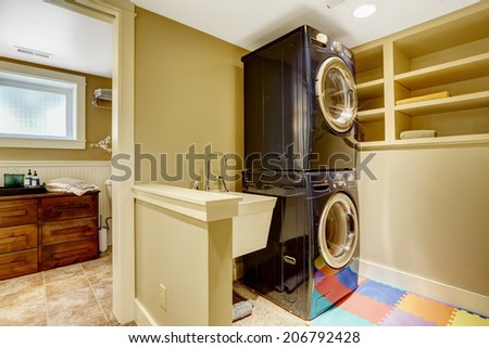 Small laundry area in bathroom. View of black modern appliances