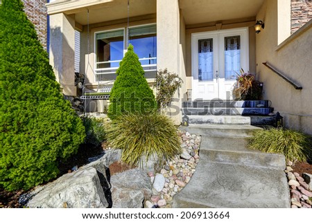House entrance porch with white door and stairs. View of walkway and with landscape