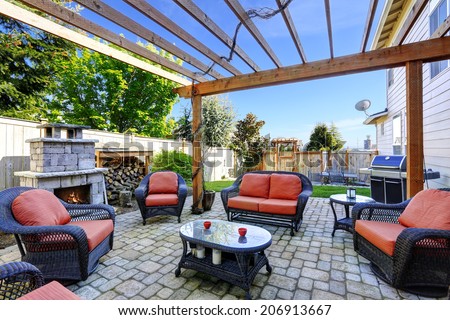 Backyard cozy patio area with wicker furniture set and  brick fireplace
