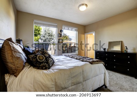 Bedroom with windows and black dresser. View of bed with pillows and blanket