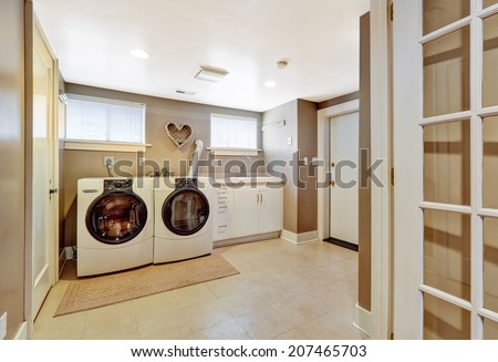 Spacious laundry room with tile floor and light grey walls. Furnished with modern appliances