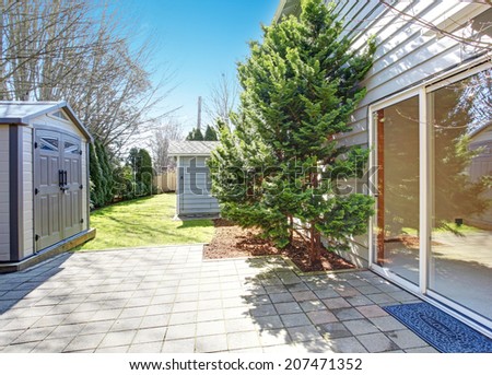 House backyard during summer. View of walkout deck and small shed