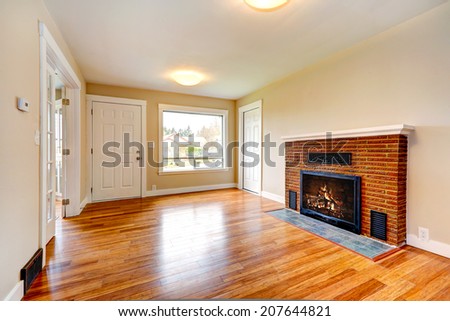 Bright empty living room in soft ivory color with new hardwood floor and brick background fireplace