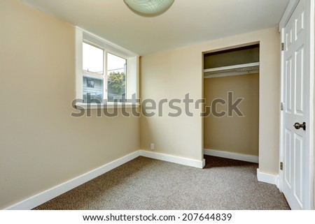 Small empty room with window and carpet floor. Room has closet