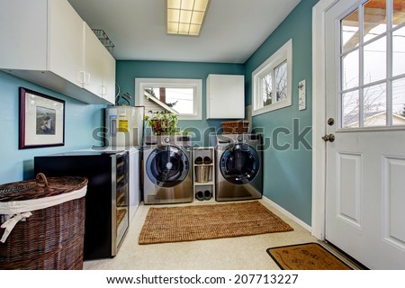 Light blue laundry room with modern steel appliances and white cabinets