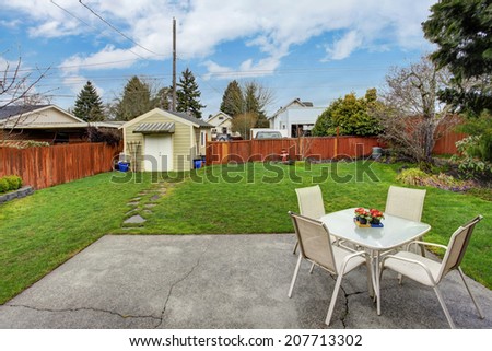 Fenced backyard with small patio area and shed
