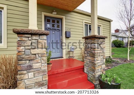Entrance porch with black door and red stairs. Stone base trim columns