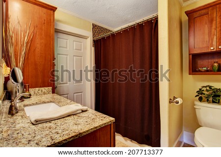 Bathroom interior with granite top vanity cabinet and brown curtains