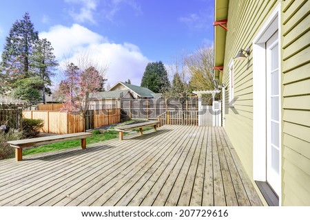 House backyard walkout deck with two wooden benched during early spring