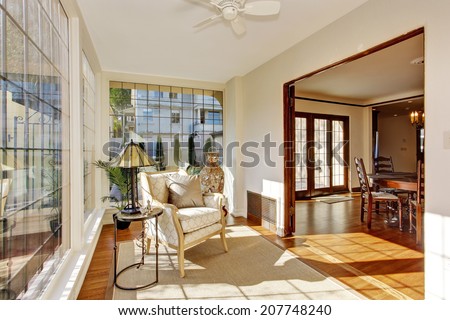 Bright sun room in soft ivory with antique chair and and small table