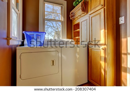 Small laundry room with wooden cabinet, white laundry appliances