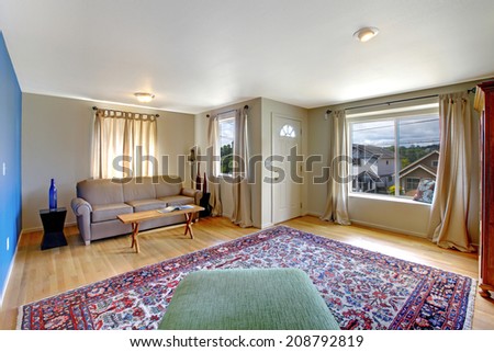 Living room with bright blue  wall. Furnished with green chair, beige sofa and rustic coffee table