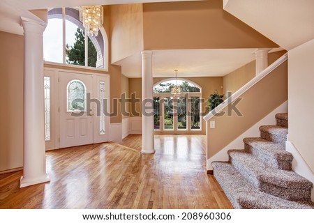 Beautiful entrance hall with high ceiling, columns and arch window in luxury house.