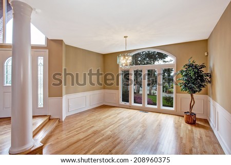 Luxury house interior. Bright  empty hallway with large window and column. Decorated with fake tree in corner