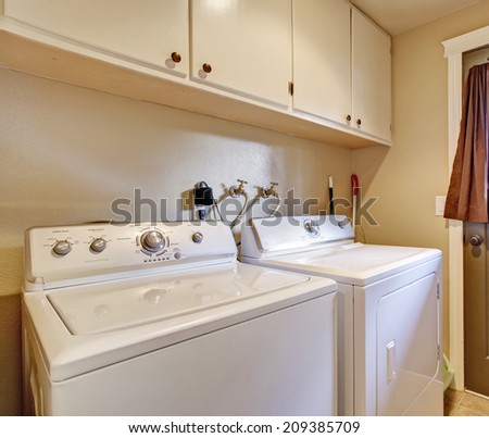 Simple laundry room with appliances and cabinets. View of exit door to backyard
