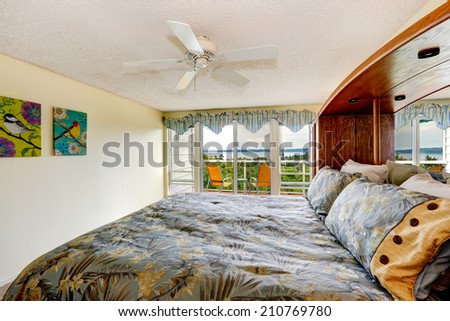 Bright bedroom with walkout deck. View of bed with floral bedding