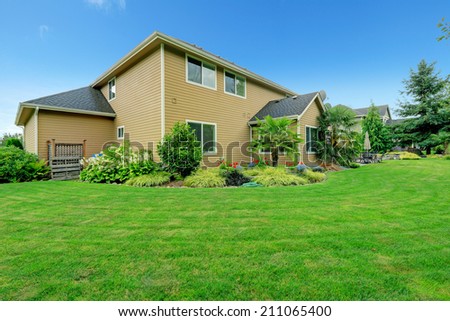 Beautiful backyard landscape with large green land and flower beds