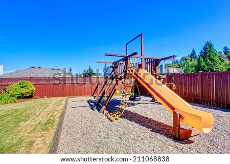 Fenced backyard with lawn and playground for kids.