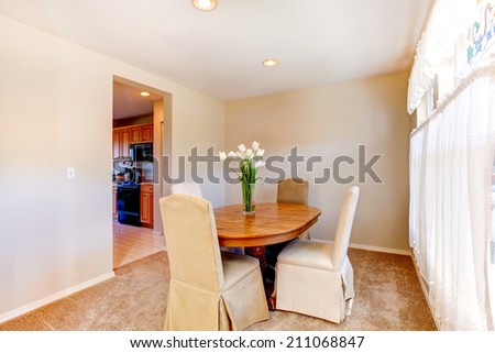 Wooden dining table decorated with fresh tulips in soft ivory room