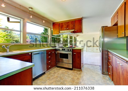 Kitchen room in empty house. View of wooden storage combination with SS-appliances