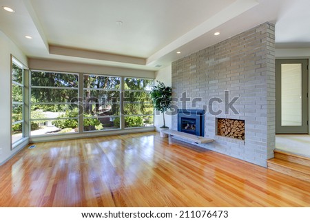 Empty house interior. Living room with glass wall. View of brick wall with fireplace
