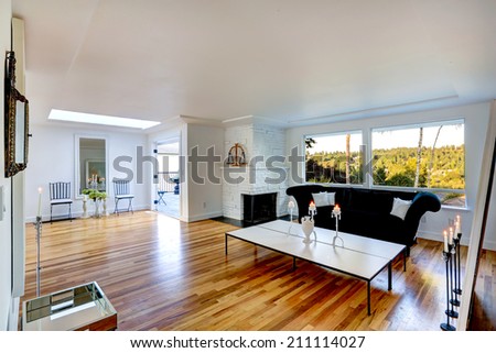 Bright living room interior with white brick fireplace. Furnished with black sofa and table