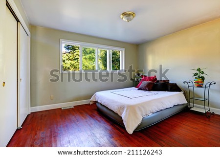 Bedroom with bright hardwood floor. View of bed with iron frame nightstands