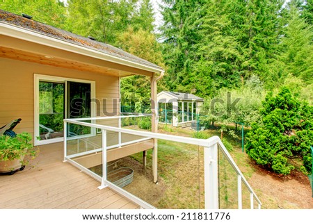 Walkout deck with glass railing. View of backyard with small shed