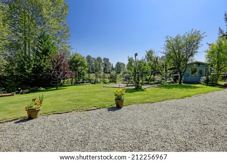 Countryside house with large backyard. Green landscape with patio area and shed