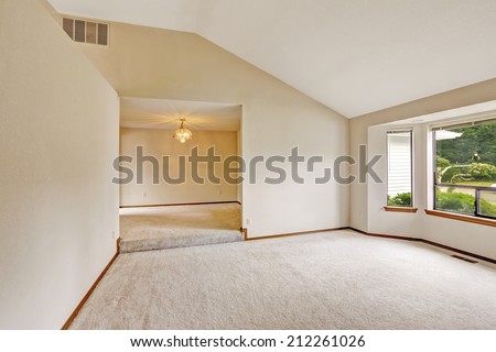 Empty house interior with open floor plan. Bright room with windows and soft ivory carpet floor