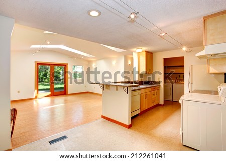 Empty house interior with open floor plan. Living room with vaulted ceiling and skylights. View of kitchen area