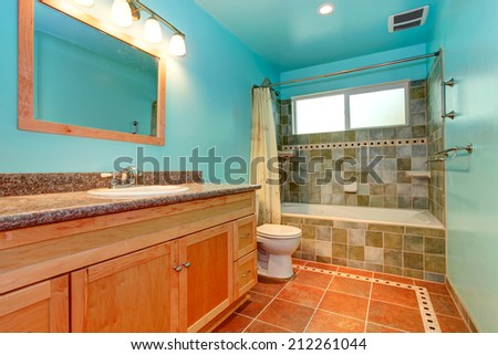 Bright blue bathroom interior with green tile wall trim and orange tile floor