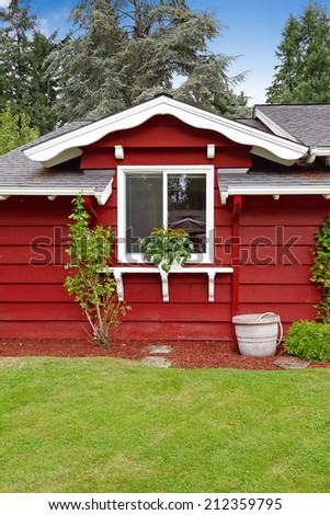 Bright red American classic country side house wall with white window and flowers.