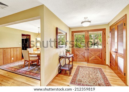 Bright hallway with hardwood floor and carved wood entrance door