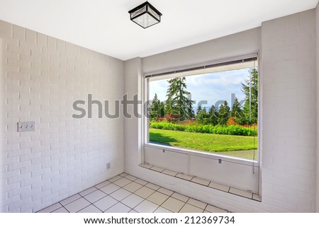 Empty dining room with beautiful window view. Tile floor and painted white brick walls. Build in 1952. Unique old modern home.