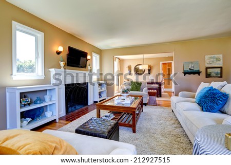 Soft beige living room with white furniture, glass top table, cozy fireplace and tv