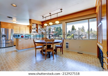 Spacious kitchen room with linoleum. Round dining table decorated with flowers