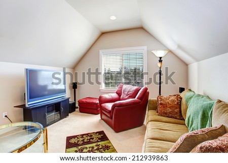 Living room with vaulted ceiling. Furnished with bright red armchair, brown sofa and tv