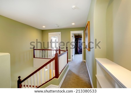 Mint upstairs hallway with carpet floor and white railings with brown trim