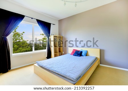 Light tones bedroom with classic bed and storage cabinet. Room decorated with purple curtains