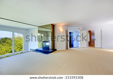 Bright empty room with  fireplace, glass wall overlooking living room with arch window