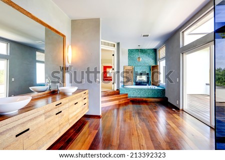 Bathroom with turquoise tile trim and fireplace. View of wooden cabinet with vessel sinks and mirror