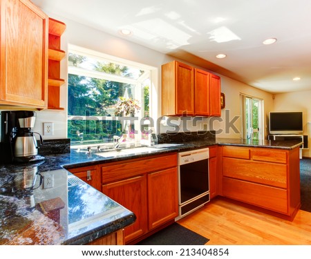 Kitchen room with wooden cabinets and black granite tops. View of living room with fireplace and tv