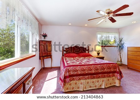 Bright bedroom interior with carved wood bed, nightstand and dresser