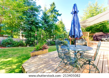 Walkout deck with patio table and umbrella overlooking backyard garden
