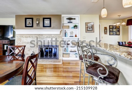 Bright dining area with fireplace and built-in storage cabinet. View of granite counter top with stools