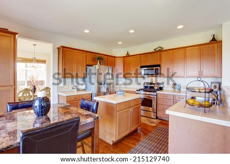 Kitchen room with granite top dining table, steel appliances and small kitchen island