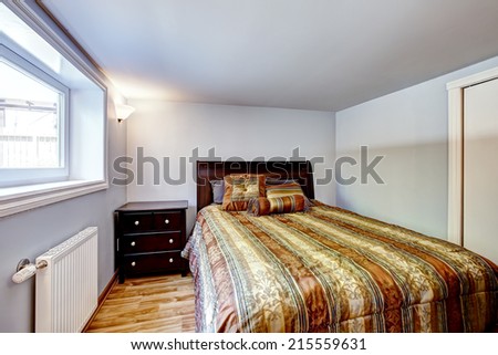 Beautiful bed with stripped brown bedding and nightstand in light blue room